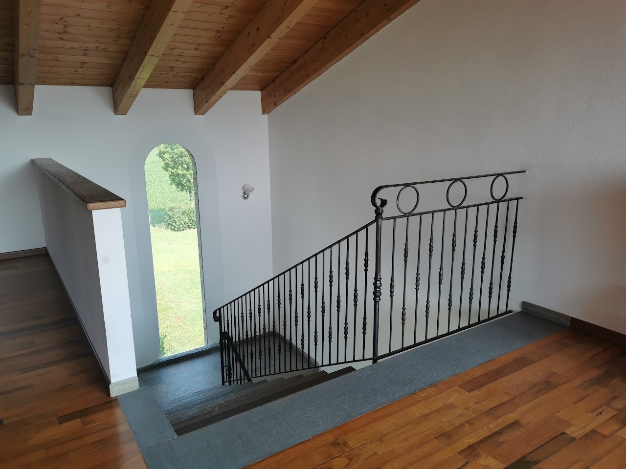 Scala in legno con ringhiera in ferro battuto e finestra ad arco